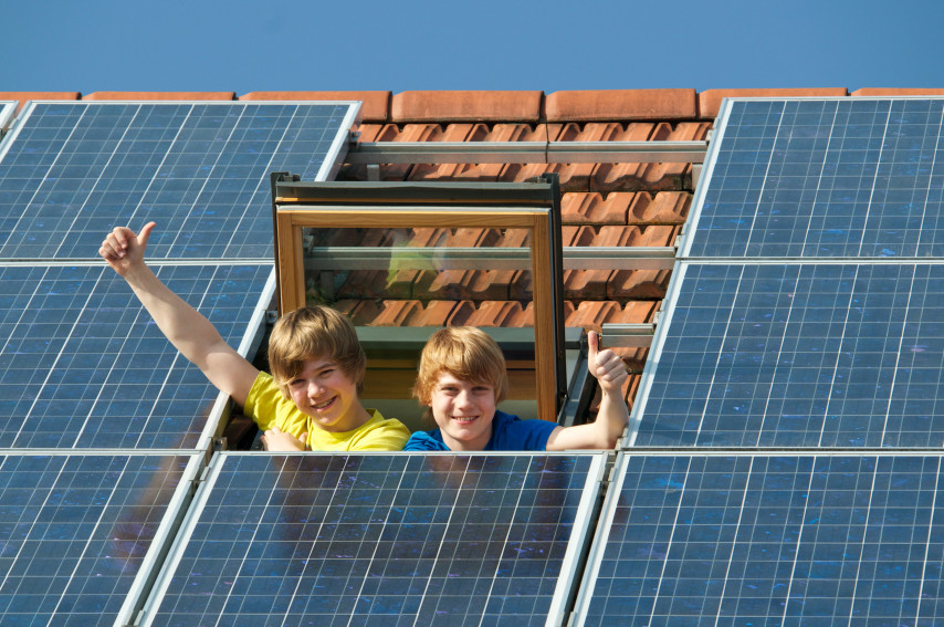 Glückliches Ehepaar vor dem Haus mit eigener Solaranlage