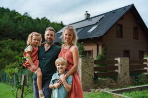 Glückliche Familie vor Einfamilienhaus mit Solaranlage
