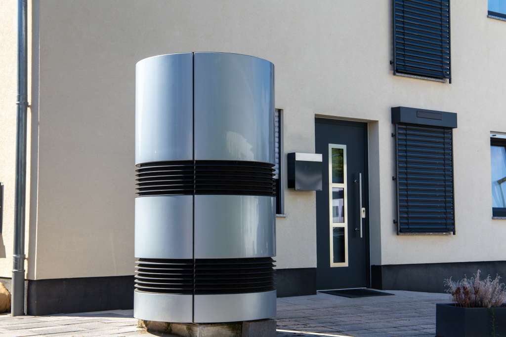 Moderne Luft-Wasser-Wärmepumpe vor einem Wohnhaus
